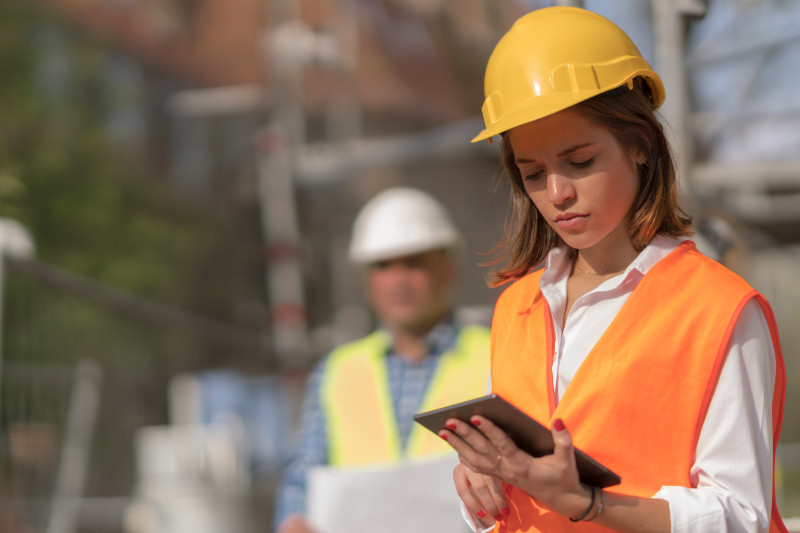 woman working on a construction site and holding a smart device